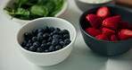 Fruit, bowls or nutrition with natural organic food or ingredients in kitchen for diet in home. Top view, strawberries and blueberries with mix recipe for health breakfast, vitamins or fiber in house