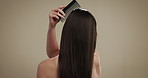 Back, hair care and comb with woman in studio for salon treatment, volume and growth. Shine, shampoo and hairdresser tools with person on background for aesthetic, cosmetics and keratin glow