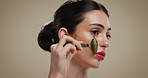 Woman, jade roller and beauty in studio with skincare for circulation, anti aging and wellness on background. Girl, person and stone tools for cosmetics, self care or routine for dermatology benefits