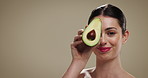 Skincare, beauty and woman with avocado in studio for natural, glow or moisturizing benefits. Cosmetic, mockup space and person with fruit for dermatology routine with hydration by brown background.