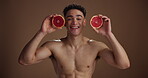 Face, man and grapefruit for skincare with smile for vitamin c, natural detox and studio background. Portrait, male person and topless with fruit, organic ingredients and glow for dermatology results