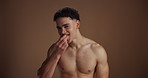 Face, eating and man in studio, kiwi and wellness with nutrition on brown background. Portrait, space and happy person with organic fruit, beauty and natural skincare with treatment and healthy