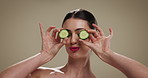 Happy woman, face and cucumber with skincare in studio for beauty on a studio background. Portrait, female person or model with smile for natural organic vegetables, diet or facial treatment on space