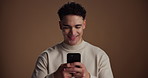 Internet, smartphone and man in studio, typing and social media with app on brown background. Mobile user, space and happy person with cellphone, connection and message to contact, chatting and email