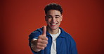 Happy man, face and winning with thumbs up in studio for good job or well done on a red background. Portrait, male person or model with smile, like emoji or yes sign for OK or success on mockup space