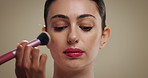 Woman, makeup brush and beauty in studio with foundation, self care and application on background. Girl, facial concealer and powder for cosmetics, change and tools for aesthetic transformation