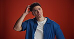 Thinking, man and confused with question in studio for doubt, uncertain and solution to memory loss. Puzzled, person and scratching head on red background for wondering, decision and problem solving