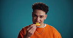 Face, eating and happy man with orange, space or fashion in studio on blue background. Portrait, cool and model laughing with fruit for healthy diet, nutrition or wellness with vitamin c or benefits