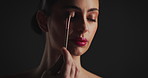 Makeup, brush and woman in studio with eyeshadow, beauty or facial routine with products. Cosmetics, self care and female person with tool for face cosmetology treatment for glow by black background.