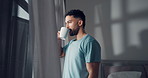 Morning, thinking and man with coffee by window to start day, smile and relax in home bedroom. House, happy person and drinking tea beverage for inspiration, reflection and view from apartment