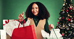 Christmas, shopping and face of woman in studio with gifts, tradition or bags for holiday discount. Happy, customer and excited female person with retail sale for xmas presents by green background.