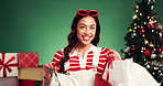 Christmas, happy and face of woman with shopping in studio with gifts or bags for holiday discount. Excited, customer and person with retail sale for xmas presents or tradition by green background.