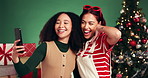 Friends, selfie and women in Christmas studio for memory, holiday and festive post choice. Picture, photography and people by tree for xmas celebration, social media or peace sign on green background