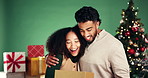 Christmas, hug and surprise with couple in studio together for reaction to gift or present. Box, celebration or wow with man and woman embracing on green background for festive tradition or holidays