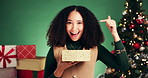 Gift, Christmas and pointing with face of woman in studio for surprise, holiday season and promotion. Festive, present and happiness with person on green background for xmas vacation and December