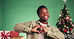 Christmas, heart and face of black man in studio for charity in festive season, holiday and tradition. Emoji, xmas and portrait of person dance for thank you, support or donation on green background