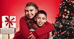 Christmas, face and happy children hug with siblings for love and holiday celebration. Girl, kids and embrace boy on xmas with brother, sister and family portrait with laugh on red studio background