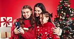 Happy mom, children or christmas with selfie in studio for photography on a red background. People, mother or kids with smile, family or hug for festive holiday, picture or capture moment together