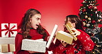 Happy girl, sister and gift box with surprise for christmas holiday in studio on a red background. Children, siblings or kids with shock or joy for santa presents, celebration or december giving