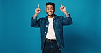 Face, happy and pointing up with man in studio for sign up, announcement and sale news. Portrait, male person and hand gesture for coming soon, show information and giveaway steps on blue background