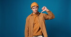 Face, grief and man with thumbs down in studio of bad news, negative feedback and wrong choice. Portrait, male person and hand gesture for poor review, rejection and fail complaint on blue background