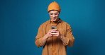 Man, phone and smile with texting in studio, notification and chat with online dating on blue background. Person, smartphone and mockup space with contact, app or happy with scroll on social media