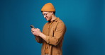 Man, phone and happy with texting in studio, notification and chat with online dating on blue background. Person, smartphone and mock up space with contact, app or smile with scroll on social media