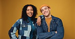 Couple, happy and face in studio with fashion, denim clothes and confidence on yellow background. Gen z people, man and woman in portrait with trendy style, love or care with interracial relationship