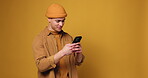 Phone, reading and typing with man in studio for social media, networking app and connection. Communication, notification update and contact with person on yellow background for space and internet