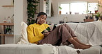 Reading, relax and weekend with black woman on sofa in living room of home for literature hobby. Book, break and storytelling with person chilling in apartment for me time, novel or wellness