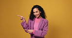 Happy woman, face and pointing with fashion in studio for advertising on a orange background. Portrait, female person or model with smile or showing option for marketing or list on mockup space