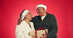 Gift box, hug and senior couple with christmas surprise in studio for marriage tradition on holiday. Love, happy and elderly man with woman for xmas presents with celebration by red background.