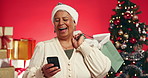 Xmas, gift and old woman in studio, smartphone and holiday season on red background. Christmas, funny meme and senior person with presents, cellphone and social media with internet, laugh or message