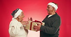 Gift box, surprise and senior couple with christmas tradition in studio for marriage tradition on holiday. Love, smile and elderly man with woman for xmas presents with celebration by red background.