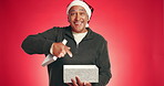 Christmas, gift and pointing with face of old man in studio for announcement, holiday season and surprise. Festive celebration, Xmas present and promotion with elderly person on red background space