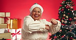 Christmas, dancing and face of senior woman in studio with gifts for holiday, xmas decoration and festive season. Happy, smile and portrait of mature person with energy to celebrate on red background