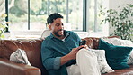 Happy, man and texting with smartphone, lounge and communication with contact, app and social media. Smile, person and chat with mobile in living room, online and typing message on website in home
