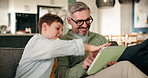 Father, boy and games on sofa with tablet, challenge and solution with puzzle in lounge at house. People, dad and child with tech, happy and application for contest, relax or bonding at family home