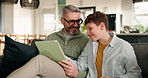 Dad, boy and games on couch with tablet, challenge and talk with puzzle in lounge at house. People, father and child with tech, happy and application with discussion, relax or bonding at family home