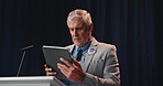 Stage, political and man with tablet, preparing and planning for presentation and government policy. Reading, speech and mature person with tech for press conference, minister and review of notes