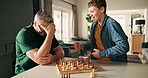 Dad, boy and play chess in home for cognitive development, challenge and celebration for checkmate. People, father and child with applause, winner or excited for goal with competition at family house