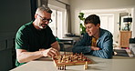 Father, boy and play chess in home for cognitive development, challenge and game strategy for bonding. People, dad and child with board, competition and contest with problem solving at family house