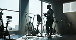 Start, stationary bike and walking with woman in gym for exercise equipment, cardio and fitness. Begin, cycling machine and performance with person for wellness club, workout and ready for training