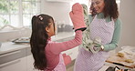 Girl, mom and high five for baking in kitchen with muffins, celebration and goals at family home. Happy people, mother and daughter with success, cupcakes or motivation for teaching at apartment