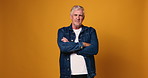 Arms crossed, face and fashion with serious man on wall background for casual clothes aesthetic. Denim jacket, outfit and style with confident mature model isolated on studio space for clothing