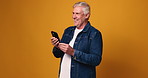Funny, smartphone and senior man in studio, internet and happiness on yellow background. Space, laughing and elderly person with cellphone, meme and humor with joke, smile and online comedy video