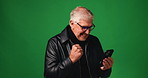Phone, senior man and celebration in studio for retirement benefit, pension annuity or lottery. Mobile, elderly person or cheering for success, win or excited with fist pump on green background space