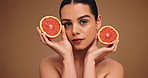 Beauty, grapefruit and face of woman in studio with health, wellness or facial routine for hydration. Skincare, natural and portrait of person with citrus fruit for dermatology by brown background.