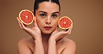 Skincare, grapefruit and face of woman in studio with health, wellness or facial routine for hydration. Beauty, natural and portrait of person with citrus fruit for dermatology by brown background.