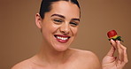 Beauty, cosmetics and strawberry with woman on wall background for diet, detox or nutrition. Face, health and wellness with happy model biting fruit on studio space for benefits of organic vitamins
